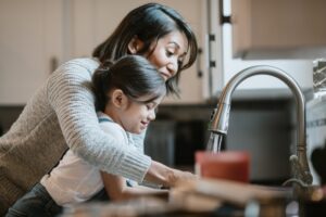 mother-and-daughter-standing-over-kitchen-sink