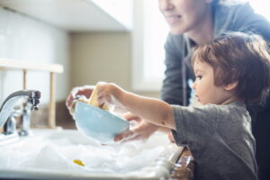 a-small-child-helps-a-parent-wash-dishes-in-the-kitchen-sink